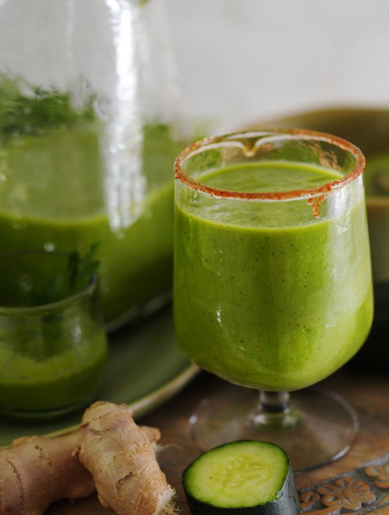 A vibrant green apple power juice in a glass, garnished with cucumber slices and a touch of ginger.