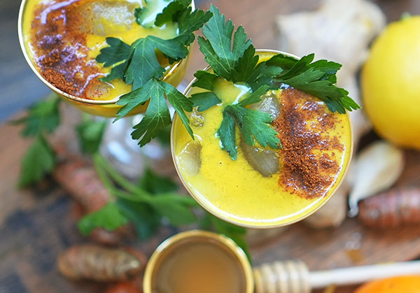 A vibrant top-down view of a golden turmeric tonic in a cup, sprinkled with warming spices.