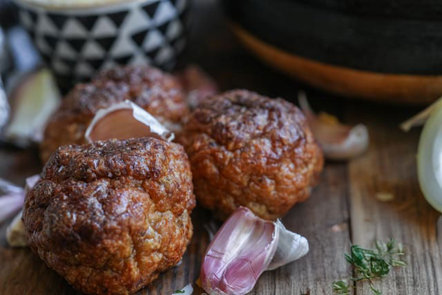 Oven baked turkey meatballs sourdough afterglow recipe golden oven baked turkey meatballs rest on a rustic wooden board with a shallot nestled beside theman earthy ingredient forward moment that speaks to slow cooking and soulful meals Perfect for storytelling prep scenes or ingredient focused shots Sourdough afterglow Rustic wooden board with golden cooked turkey meatballs and a single shallot beside them
