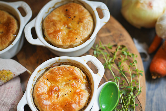 Sourdough beef pot pie in white cocottes flaky crust comfort fresh from the oven three mini beef pot pies in white cocottes sit on a wooden board their sourdough crusts perfectly golden and crisp The savory filling bubbles just beneath the surface promising warmth and comfort in every bite Sourdough afterglow Baked mini beef pot pies in white cocottes with flaky sourdough crusts, bubbling underneath and resting on a rustic wooden board