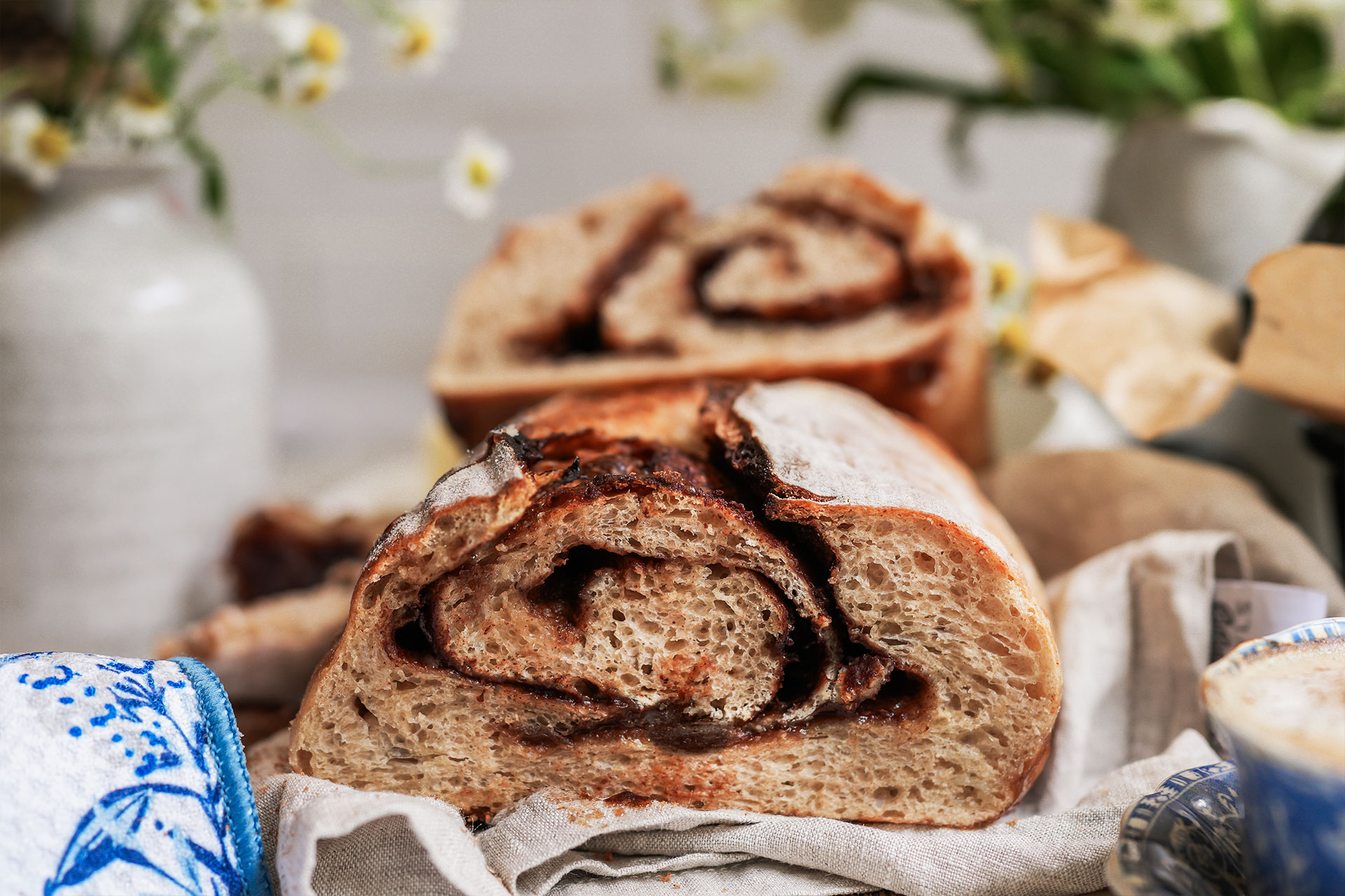 Cinnamon swirl sourdough bread resting on a linen towel, with crumb and cinnamon sugar swirl exposed