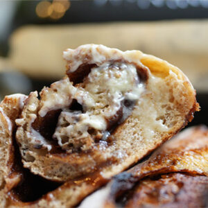 Close-up of a sliced cinnamon swirl sourdough loaf with the top portion smothered in butter, ready to eat
