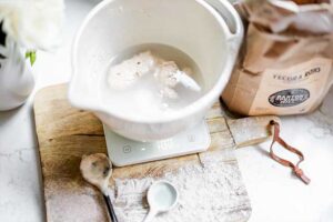 Sourdough starter and water in a glass bowl for cinnamon swirl bread