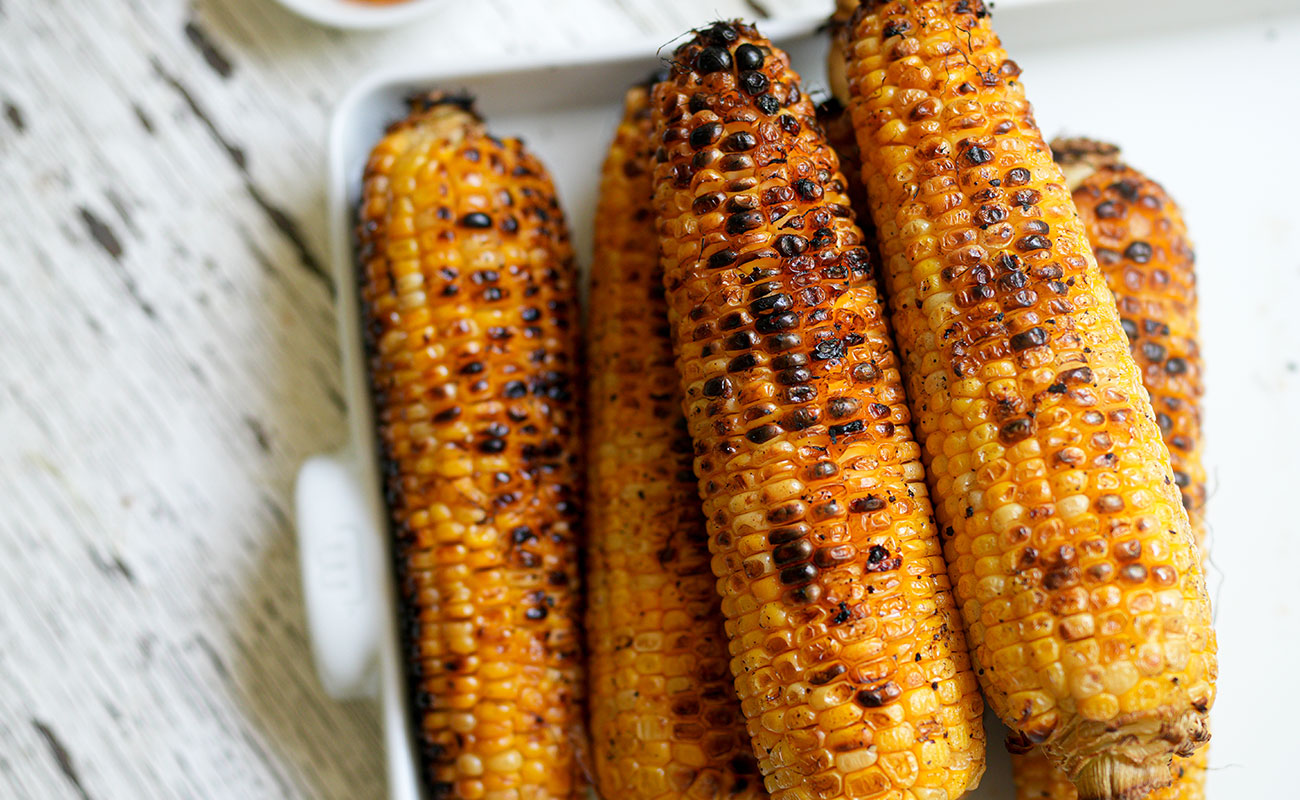Crispy chicken tacos with corn salsa golden grilled corn on the cob with beautiful char marks resting on a made in baking sheet This rustic prep moment is where the flavor begins for the creamy corn salsa in the crispy chicken taco sourdough afterglow Charred grilled corn on a Made In baking sheet, ready for slicing and salsa prep
