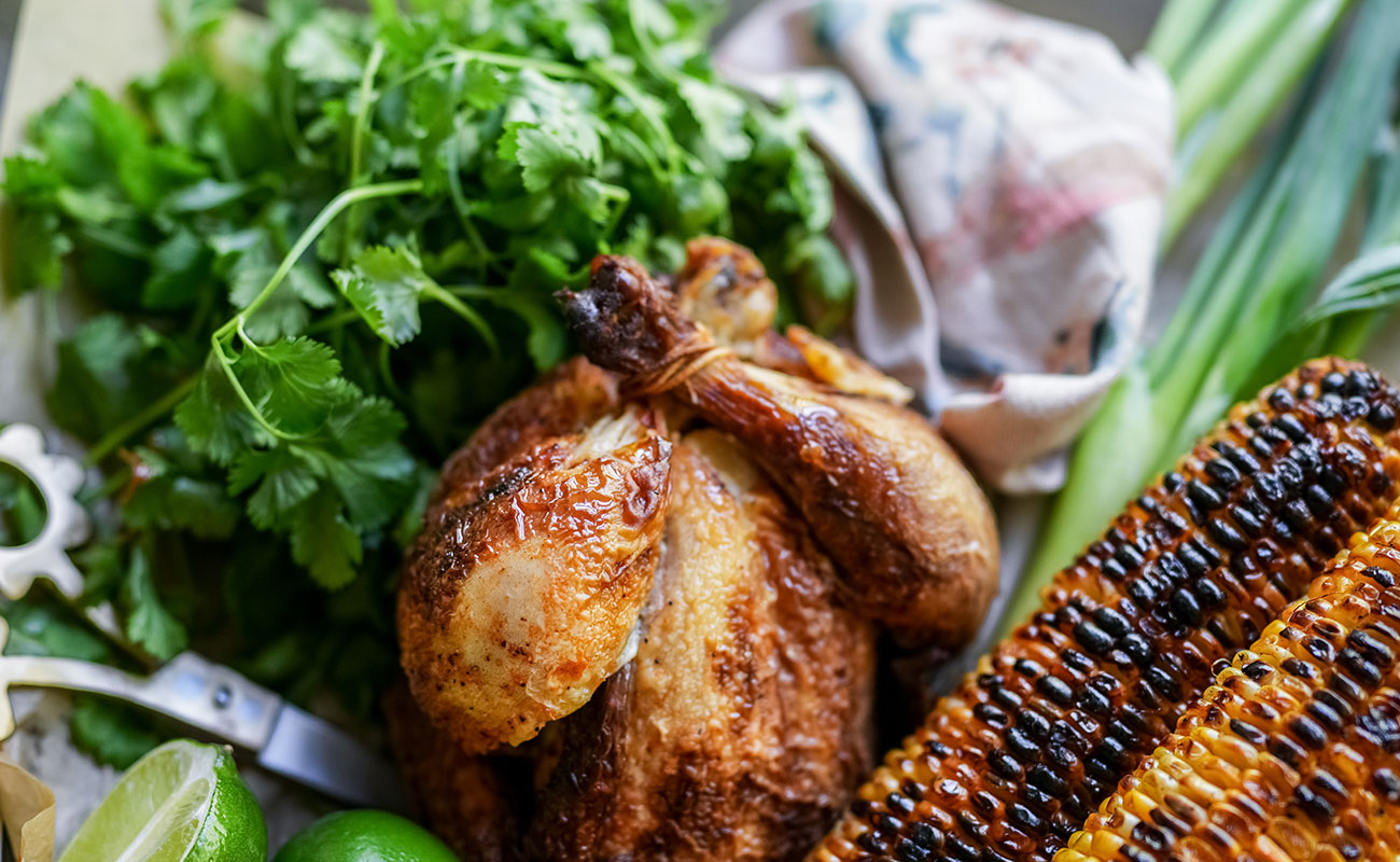Crispy chicken tacos with corn salsa a perfectly roasted rotisserie chicken sits on a prep board with charred corn bunches of fresh cilantro green onions and lime This setup captures the fresh flavorful ingredients for the taco filling in the crispy chicken tacos with corn salsa recipe Sourdough afterglow Rotisserie chicken surrounded by grilled corn, fresh cilantro, green onions, and lime—ingredients for crispy chicken tacos